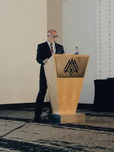 A professional speaker standing at a wooden podium during a medical or dental seminar
