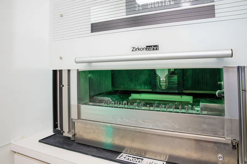 A close-up of a high-precision dental milling machine in a clinical lab setting