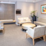 A modern waiting room with comfortable armchairs, a small round coffee table, and soft ambient lighting