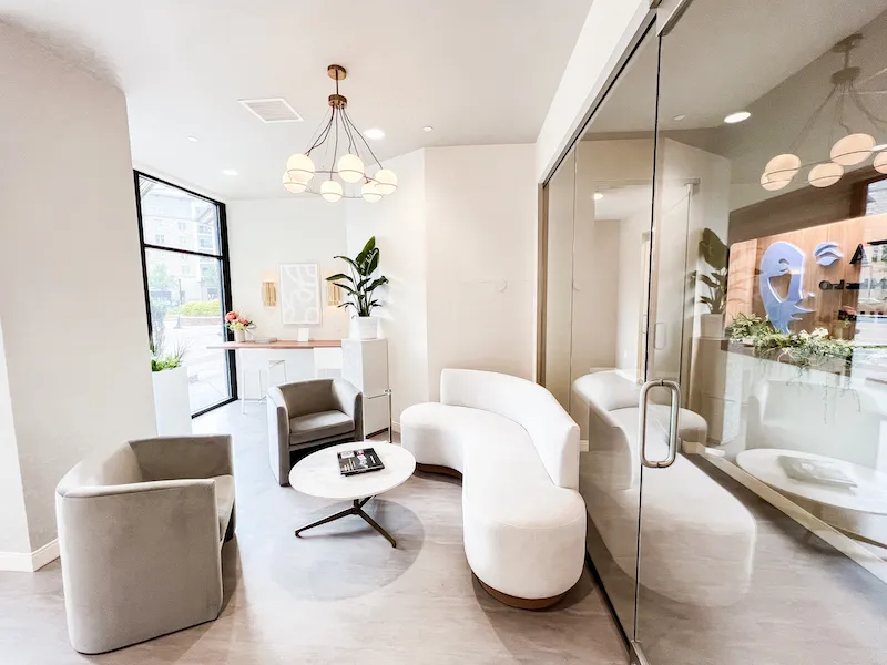 Minimalist lobby with curved white sofas, modern gray armchairs, and a large window