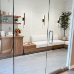 View through glass doors into a clinical workspace with wooden cabinetry and a large plant