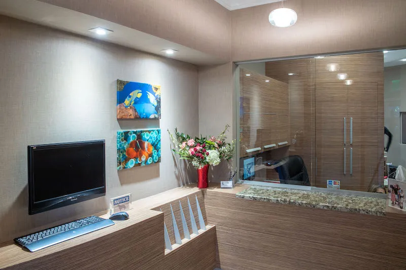 A high-end office reception counter with wood-slat detailing and a digital monitor