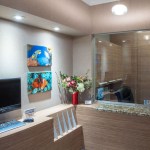 A high-end office reception counter with wood-slat detailing and a digital monitor