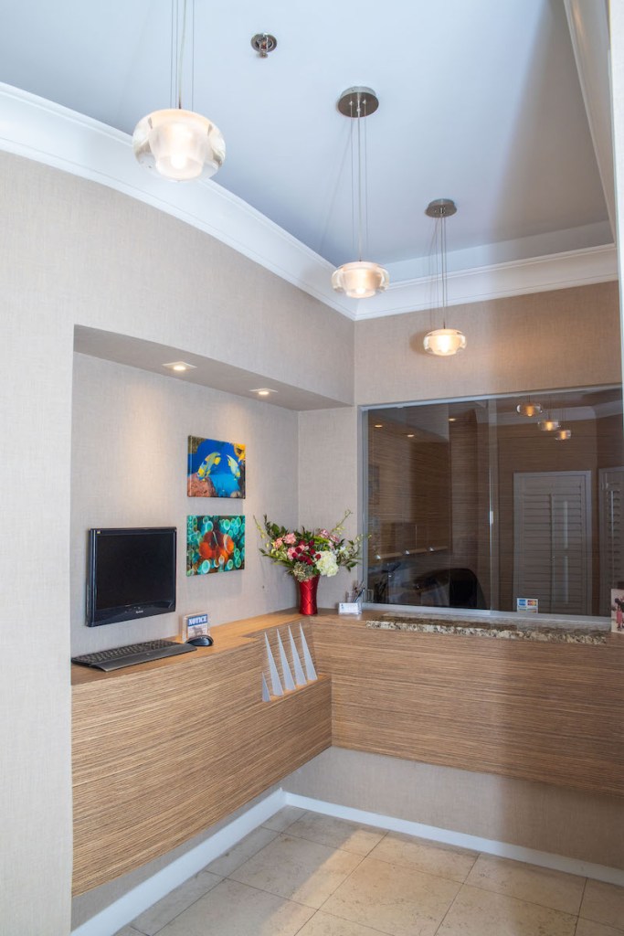 A compact clinical workstation with white cabinetry and a computer monitor built into a recessed nook