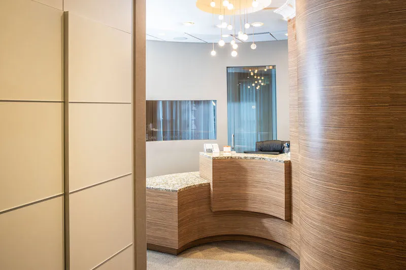 A reception area with sleek wood-paneled walls and a curved wood-grain front desk
