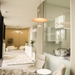 A wide view of an open-concept waiting area with modern white sofas, glass partitions, and indoor greenery
