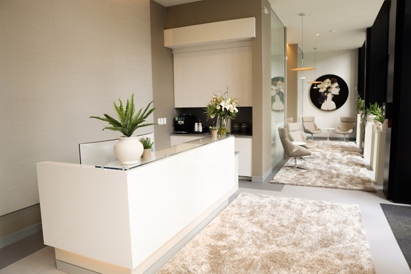 A stylish reception desk area with a marble-patterned rug and contemporary white furniture