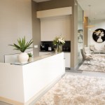 A stylish reception desk area with a marble-patterned rug and contemporary white furniture