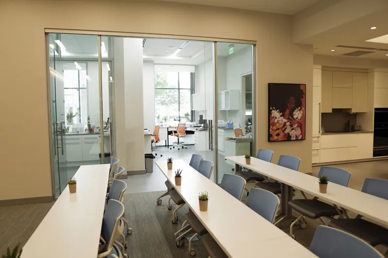 A professional training or meeting room with long white tables and blue office chairs