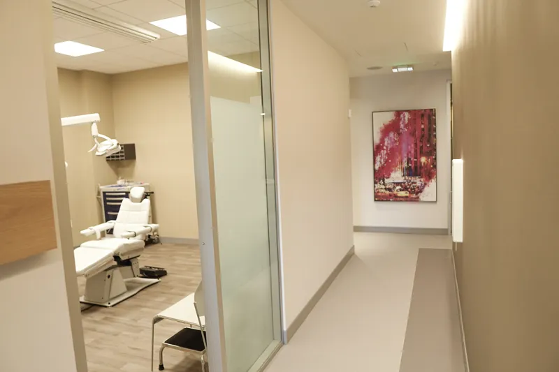 A perspective view down a clean medical office hallway with a piece of abstract red art on the wall
