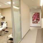 A perspective view down a clean medical office hallway with a piece of abstract red art on the wall
