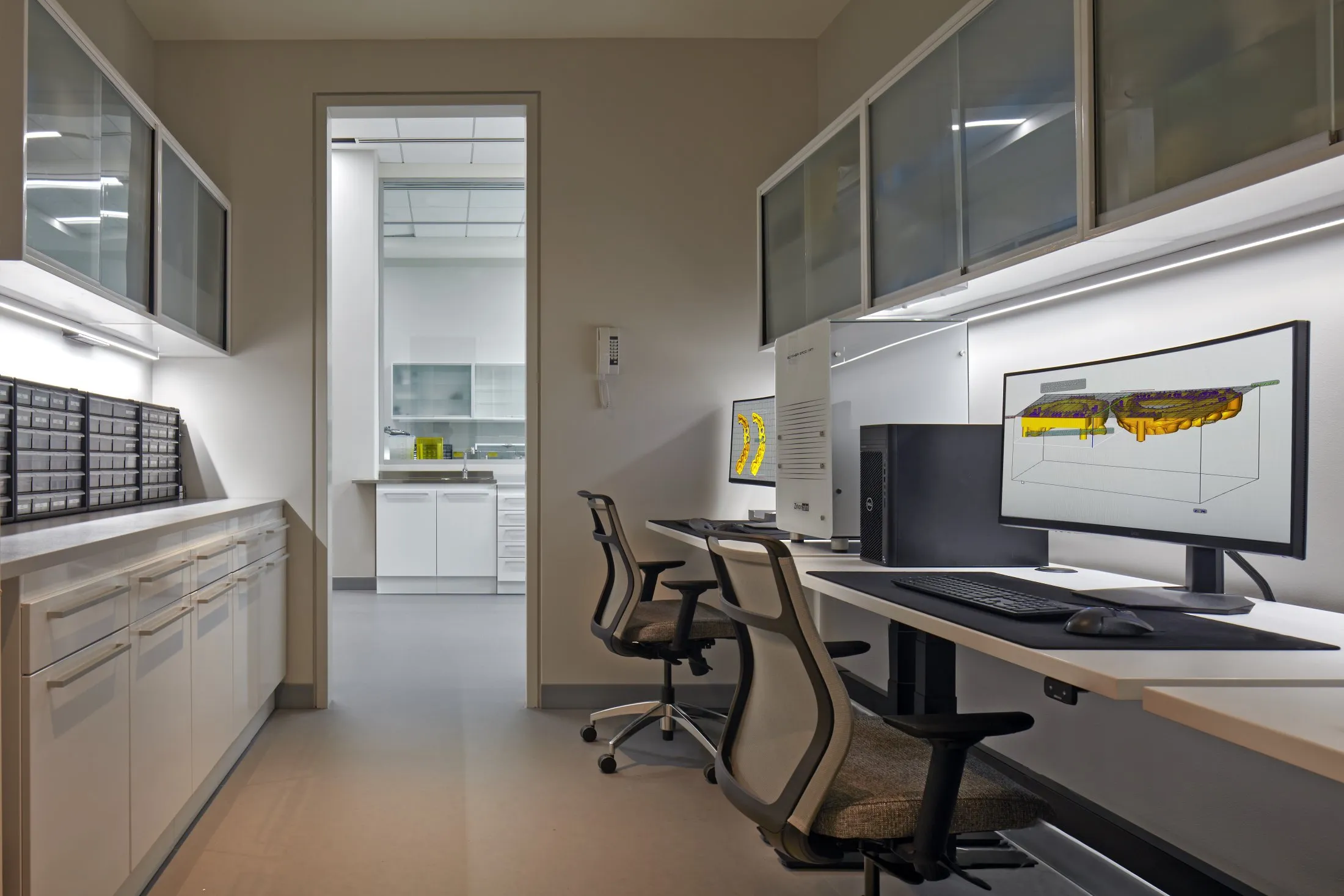 A digital dental lab with high-tech monitors displaying 3D dental scans and ergonomic office chairs